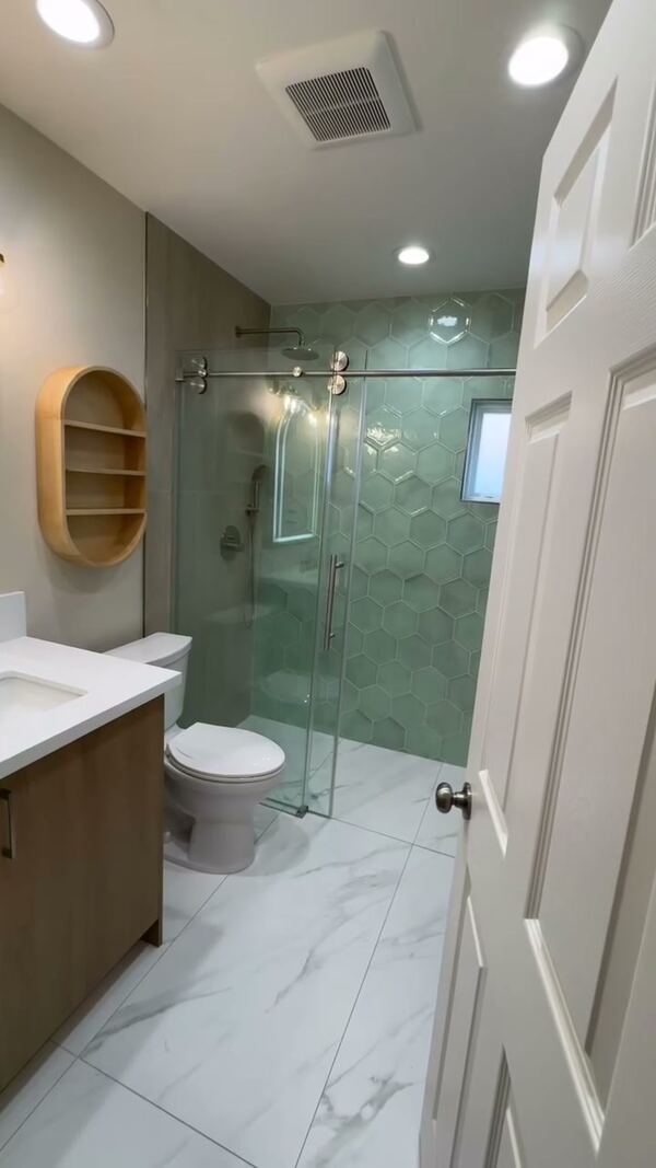 Remodeled bathroom in Alhambra with a green hexagon tile shower and a sliding glass door