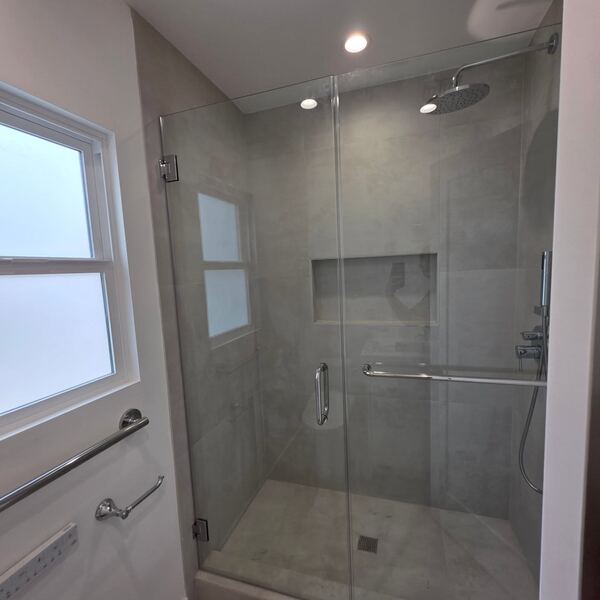 Glass shower with grey tile and a rain shower head