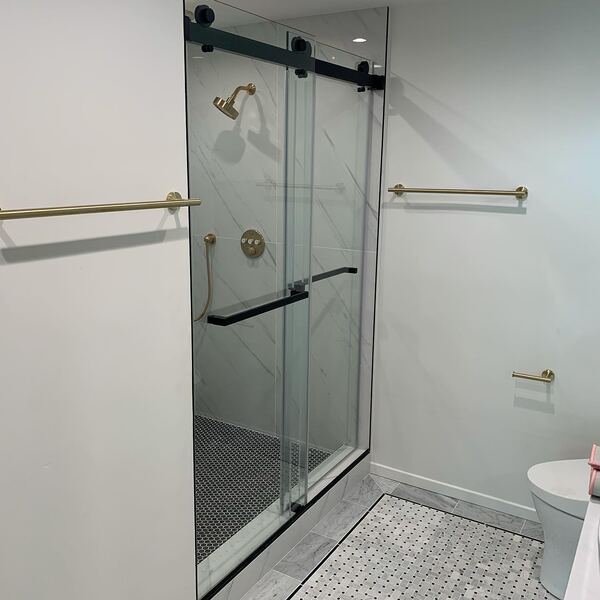 Glass shower with a black frame and brass shower head