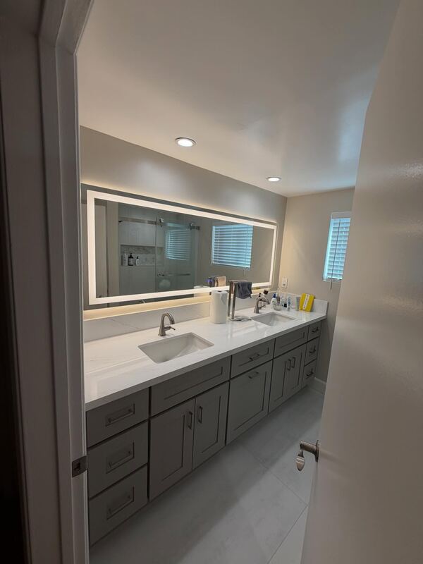 Remodeled bathroom in Arcadia, with a double vanity under a lit mirror