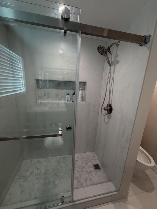 Walk-in shower with a sliding glass door and a tiled niche