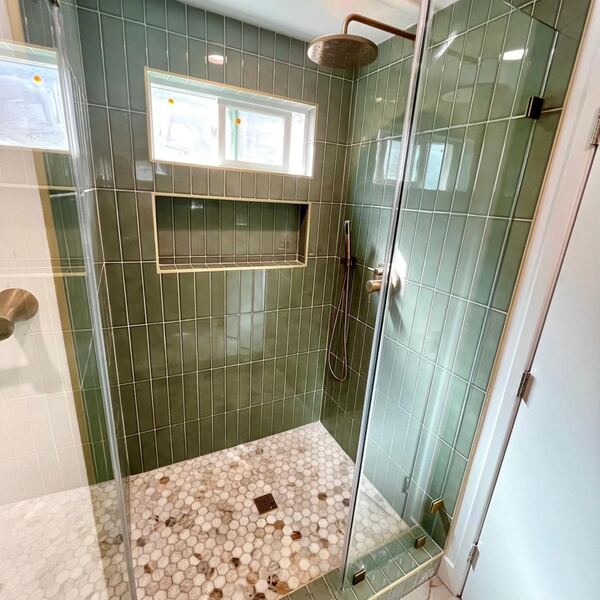 Shower in Monrovia with green subway tile and a pebble floor